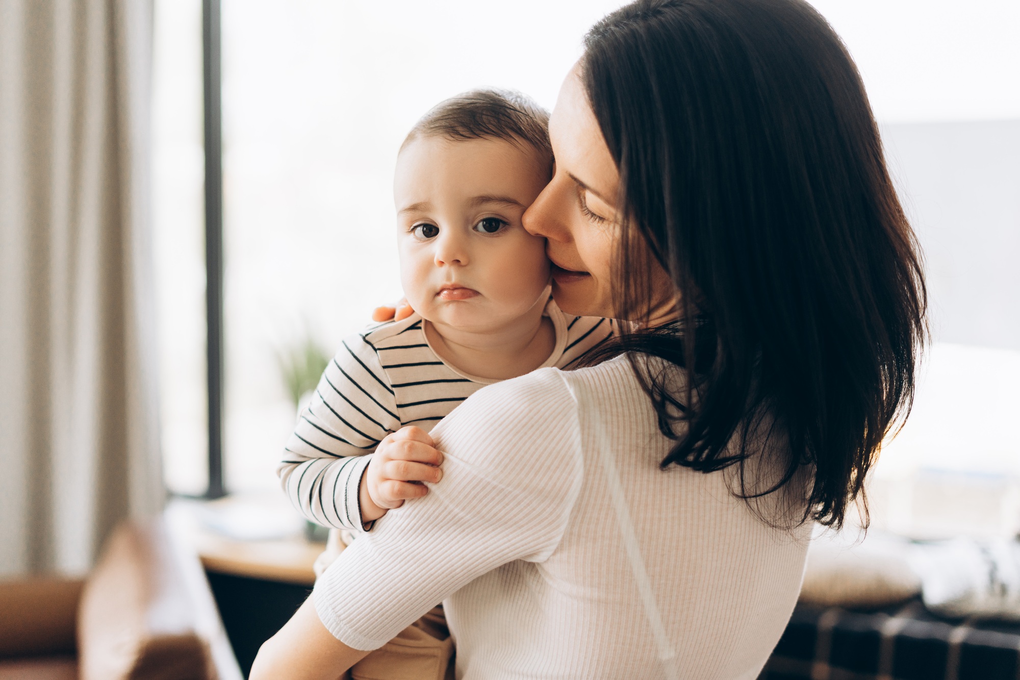 Mother holding baby, embracing and showing affection at home